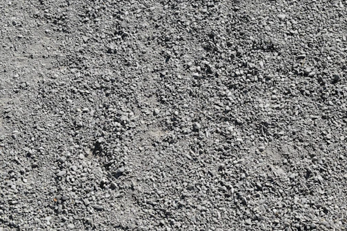 A close-up of gravel being spread evenly across a roadbed, highlighting texture and quality.