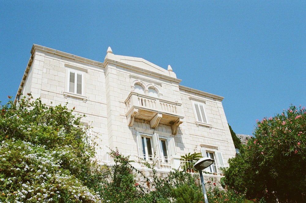 a tall white building sitting next to a lush green forest