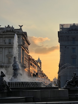 a fountain in a city with buildings in the background