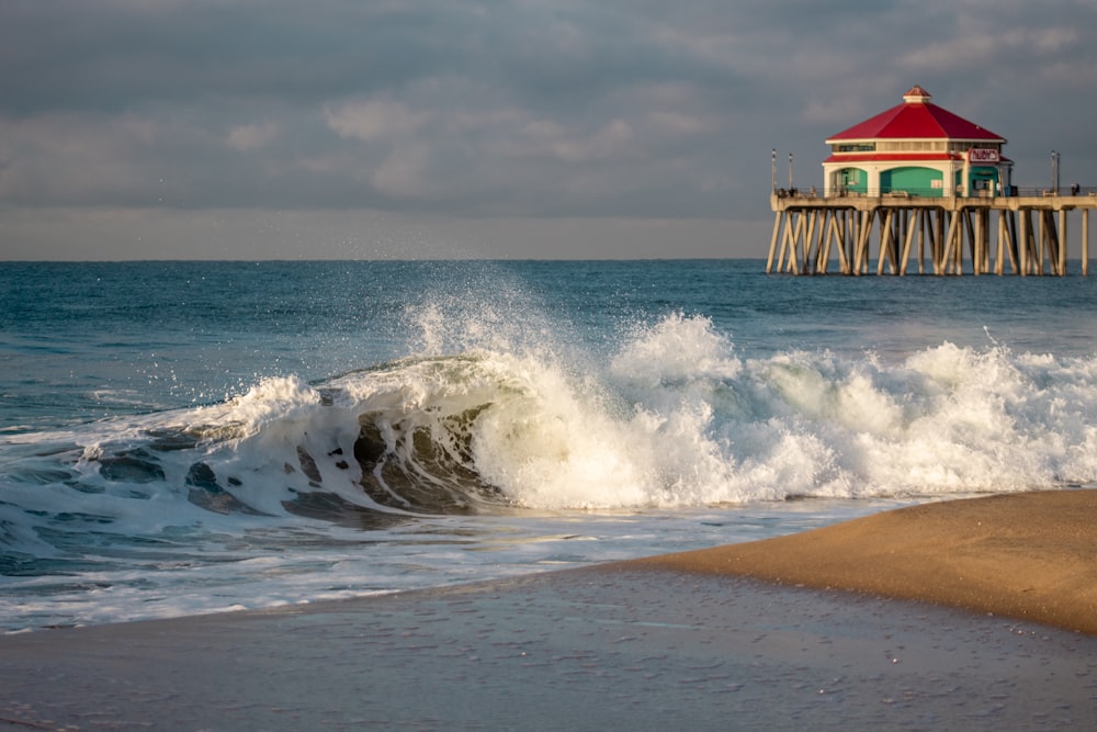 a red and white building sitting on top of a pier next to the ocean