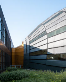 A sleek commercial building design with glass facades and greenery.