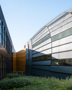 A sleek commercial building design with glass facades and greenery.