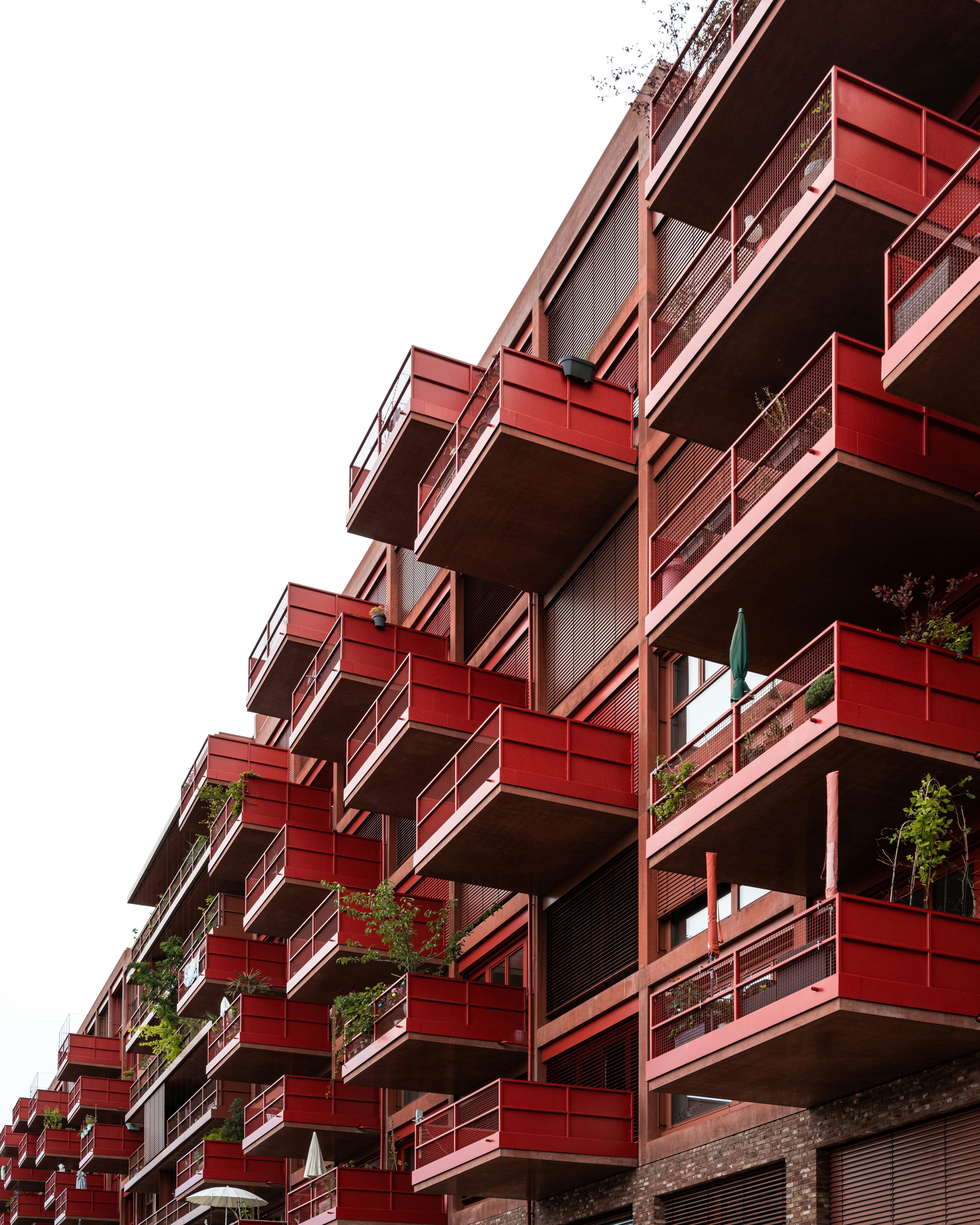a red building with balconies and plants on the balconies