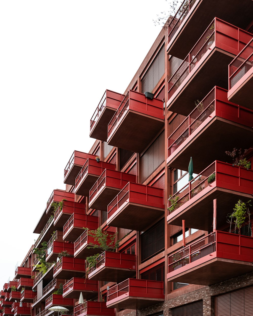 a red building with balconies and plants on the balconies