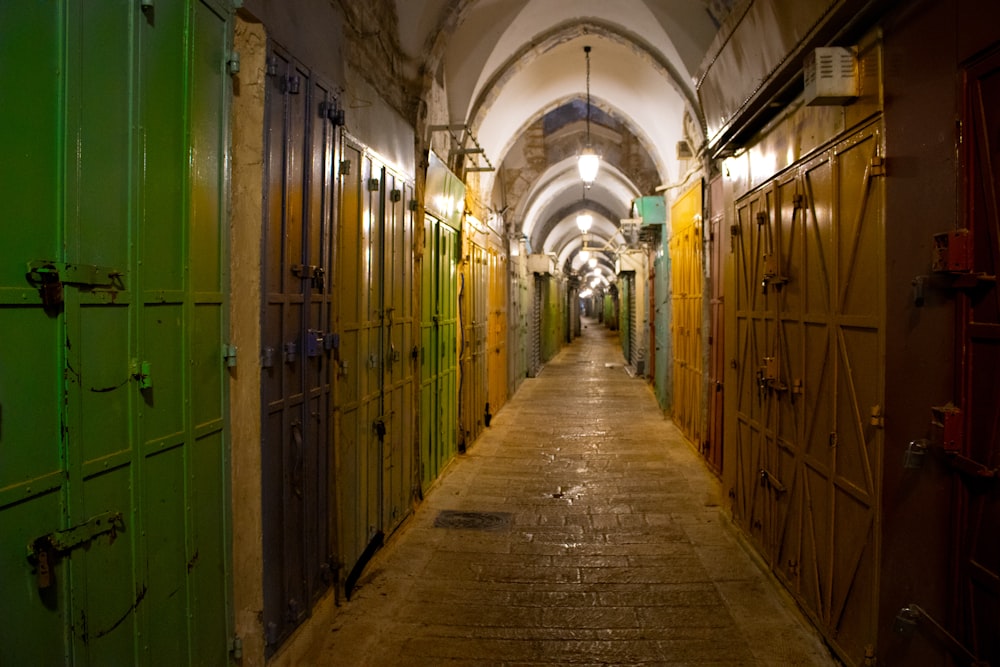 a long narrow hallway with green doors leading to another room