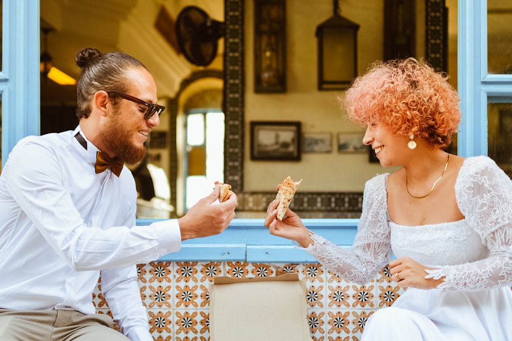 a man and woman sitting on a bench eating food