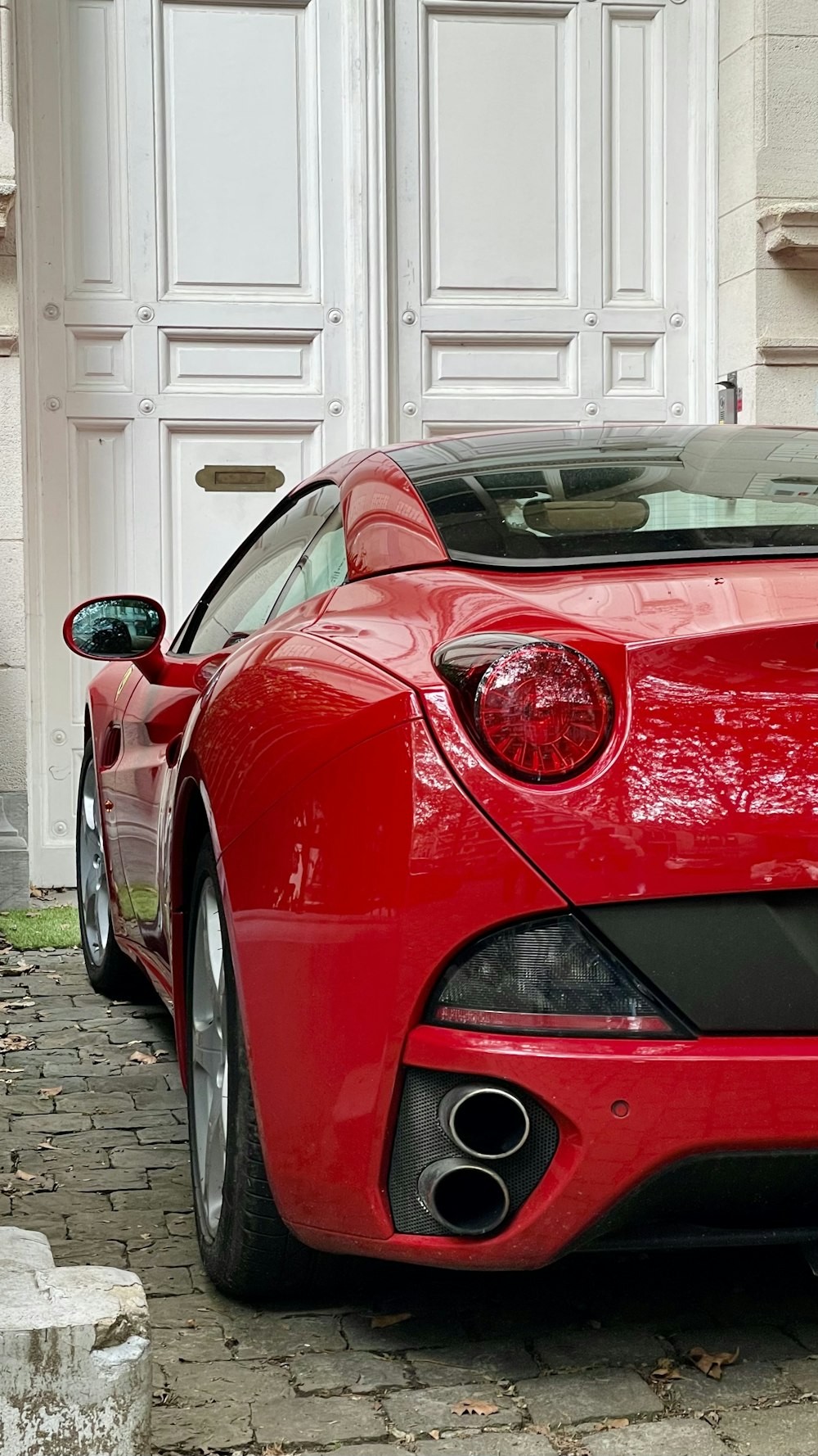 a red sports car parked in front of a white door