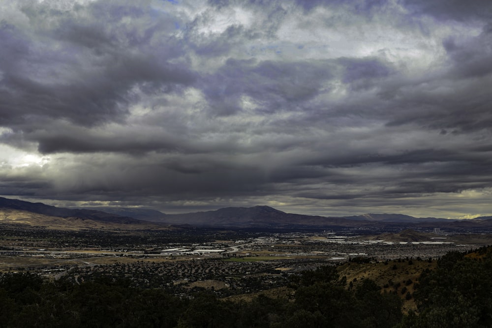 a cloudy sky over a valley with mountains in the background