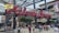 A large sign with the words 'Atlanta Braves' in red, cursive letters is suspended from a metal framework. Below, a bustling crowd of people moves about, some wearing sports apparel. The background features a multistory building with signage, including 'Xfinity' and 'Terrapin Taproom.'