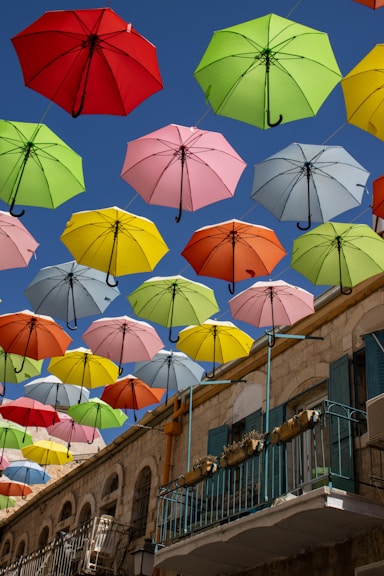 a group of multicolored umbrellas flying in the air