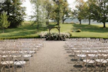 A wide shot of an elegant outdoor wedding ceremony with guests seated and a stunning floral arch.