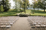A wide shot of an elegant outdoor wedding ceremony with guests seated and a stunning floral arch.