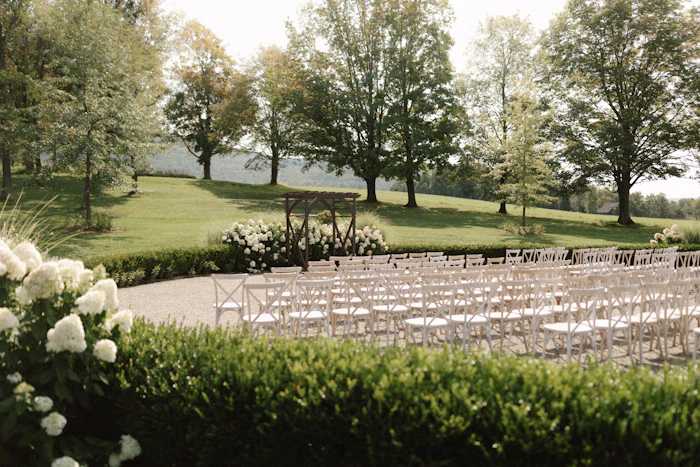 Rangées de chaises installées pour une cérémonie sur une grande pelouse arborée