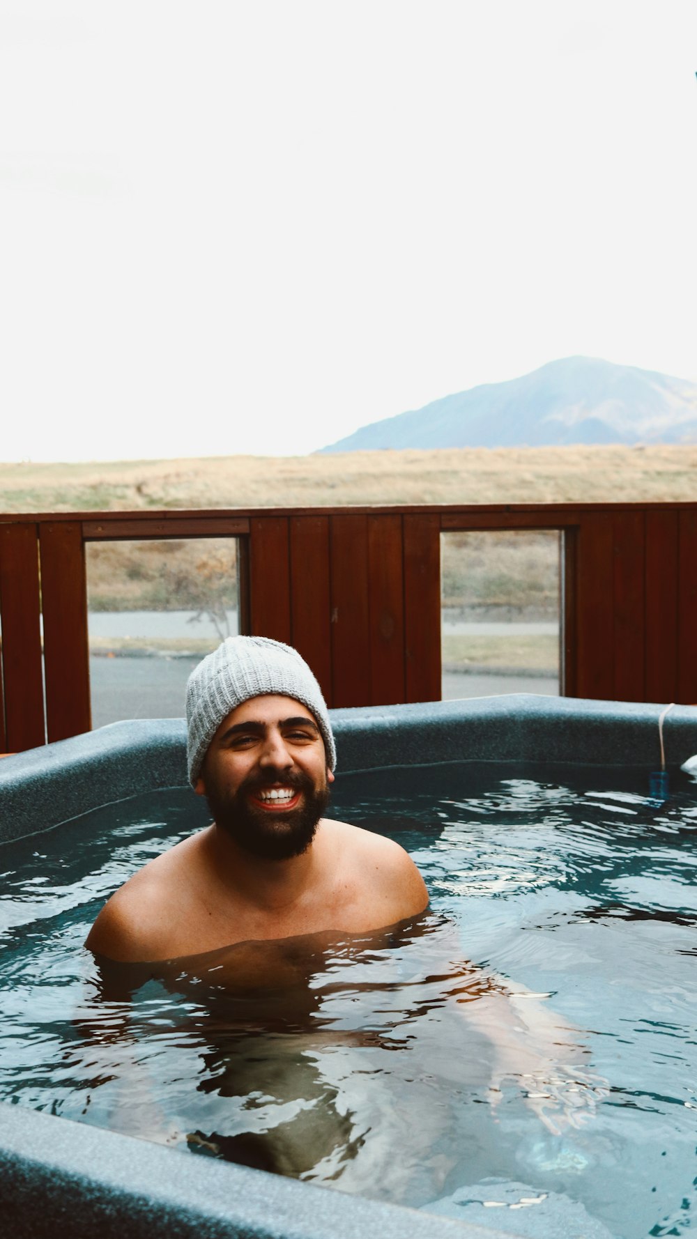 a man in a hot tub with mountains in the background