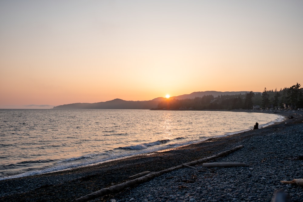 the sun is setting over the water at the beach