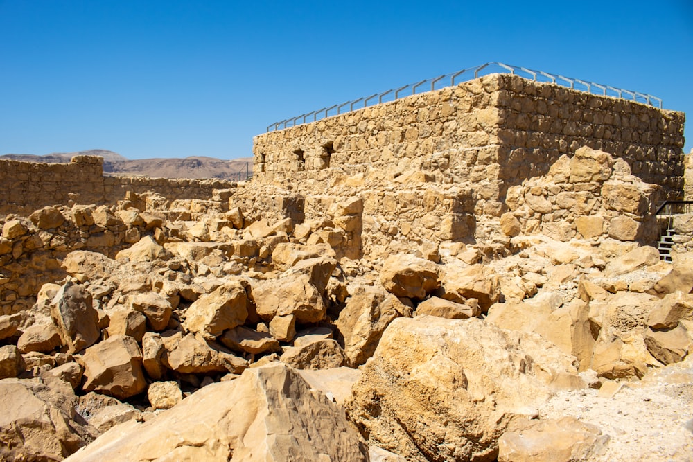 a stone building surrounded by rocks and a barbed wire fence