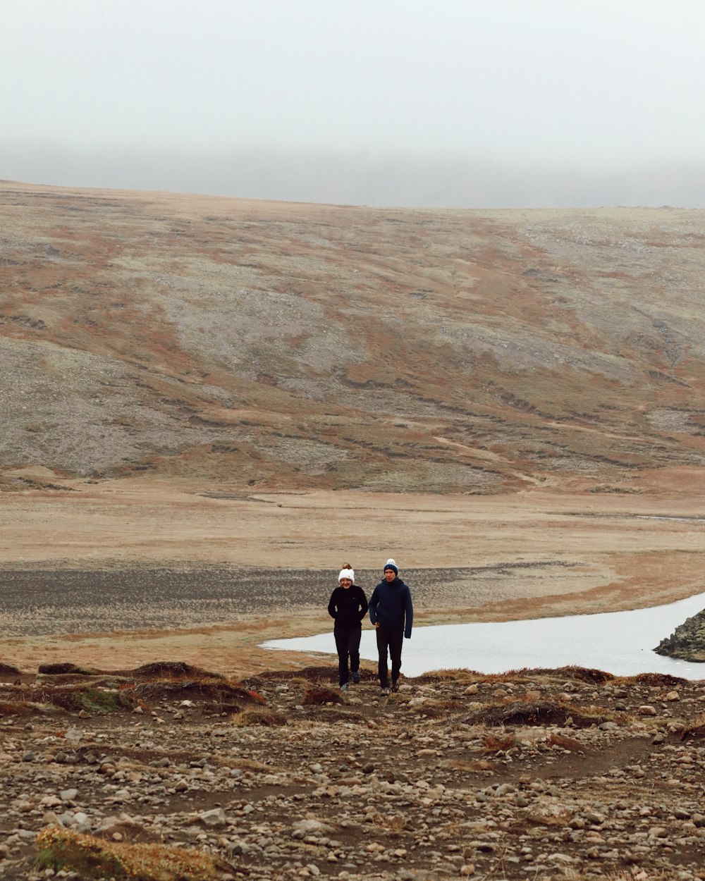 a couple of people standing on top of a dry grass field