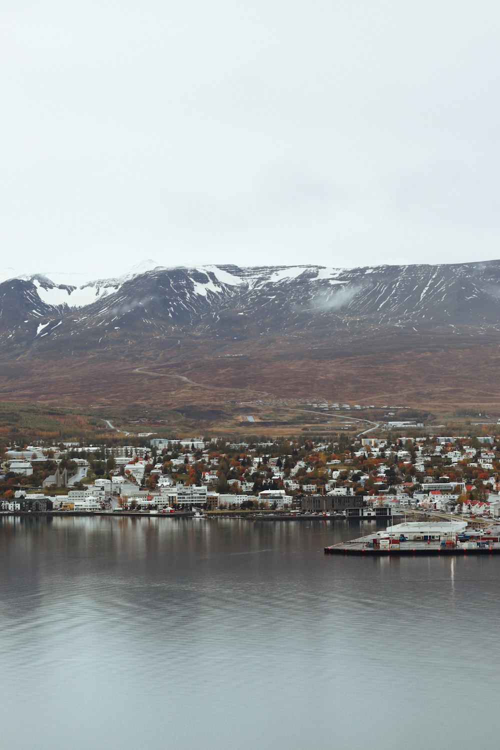 a view of a town and a body of water with mountains in the background