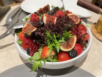 A vibrant bowl of fresh mixed berry salad with mint leaves.