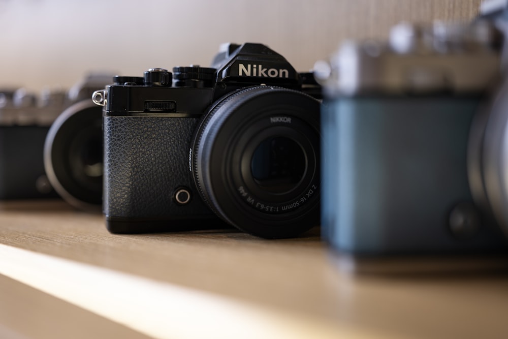 a group of cameras sitting on top of a wooden shelf