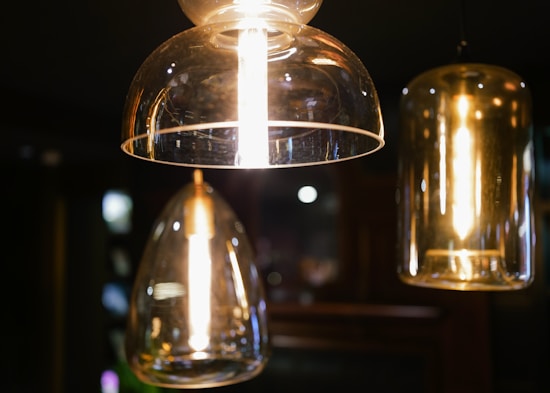 Elegant, modern pendant lights with clear glass casings hang from the ceiling, emitting a warm, ambient glow.
