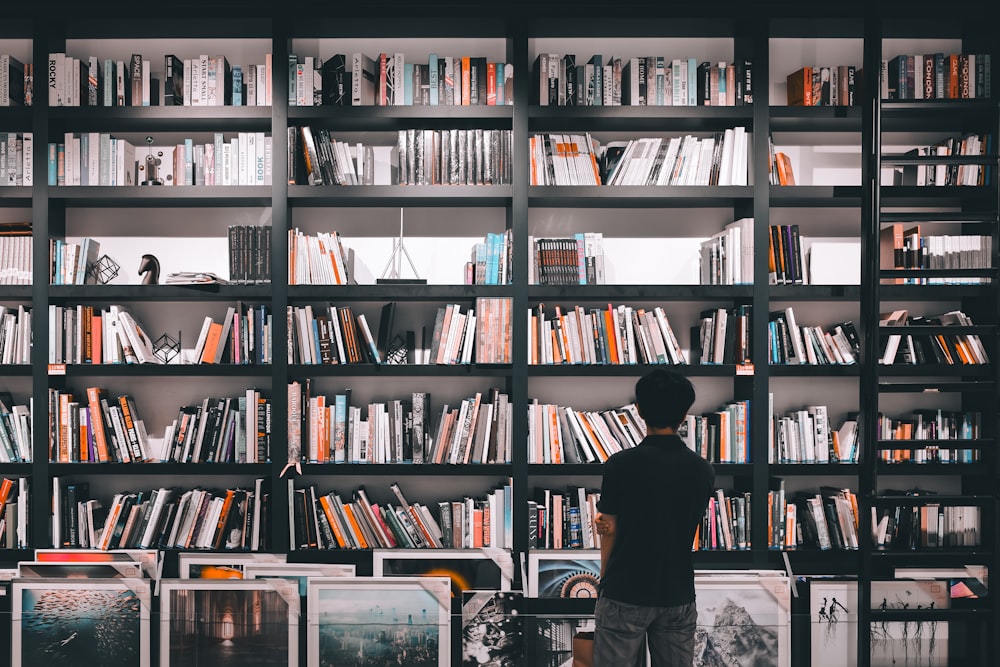 a man standing in front of a bookshelf filled with books