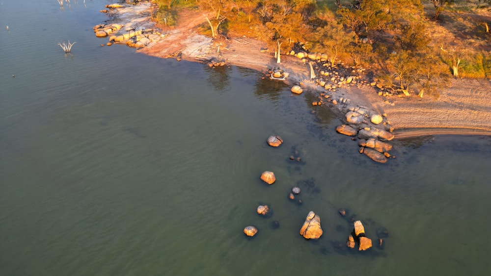 an aerial view of a lake with rocks in the water