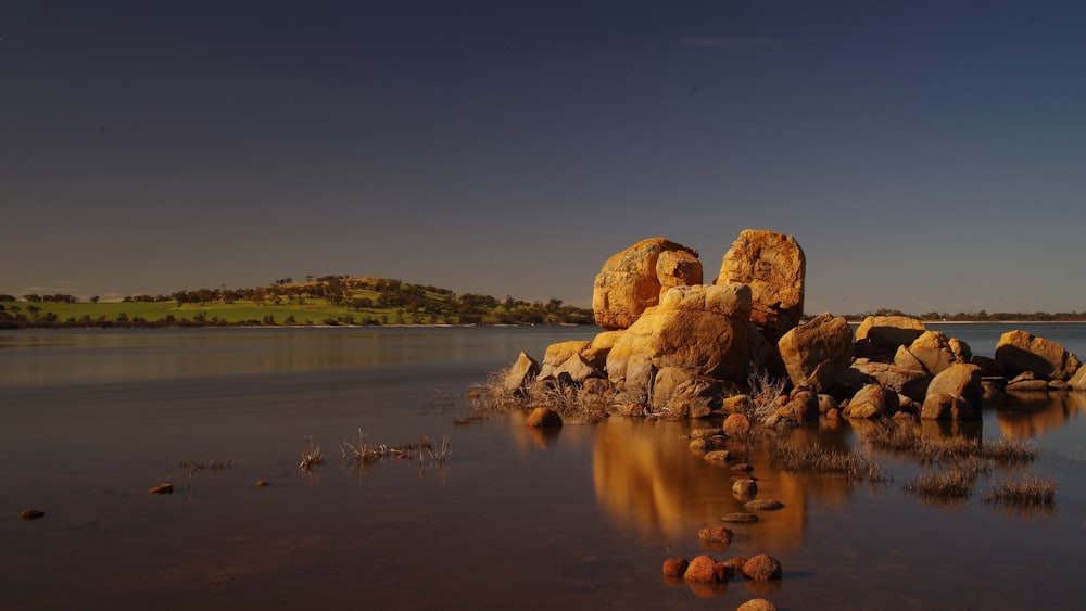 some rocks in the water and a hill in the background