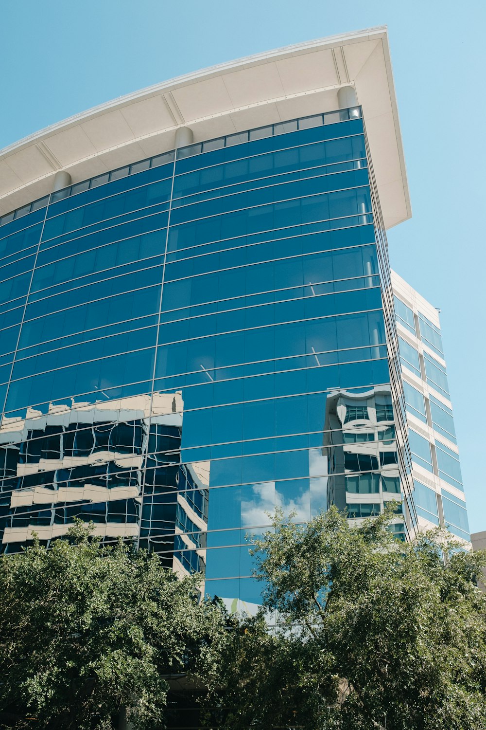 a large glass building with trees in front of it