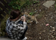 A caregiver kneeling to offer treats and affection to a shy cat during a short-stay companionship visit.