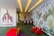 A children's playroom with vibrant, colorful wall murals featuring giraffes and jungle foliage. The room is decorated with playful elements including red toy animals and a multicolored padded cube. A table with small chairs is at the end of the room, and the ceiling has yellow recessed lights.