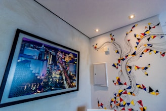 A vibrant cityscape painting framed and hanging in a cozy studio.