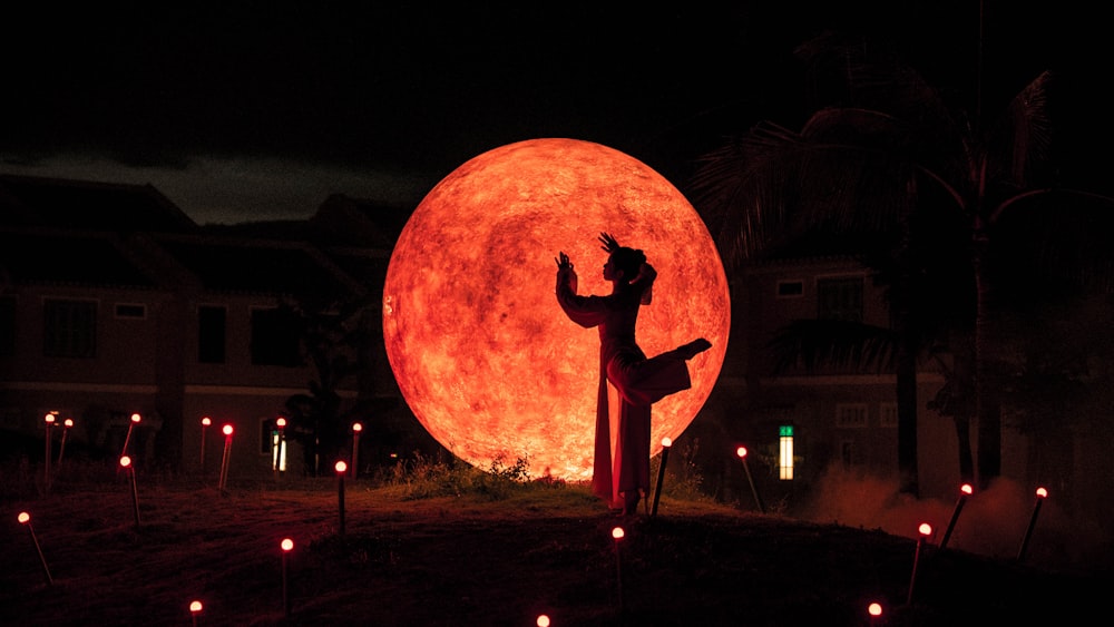 a person standing in front of a giant red moon