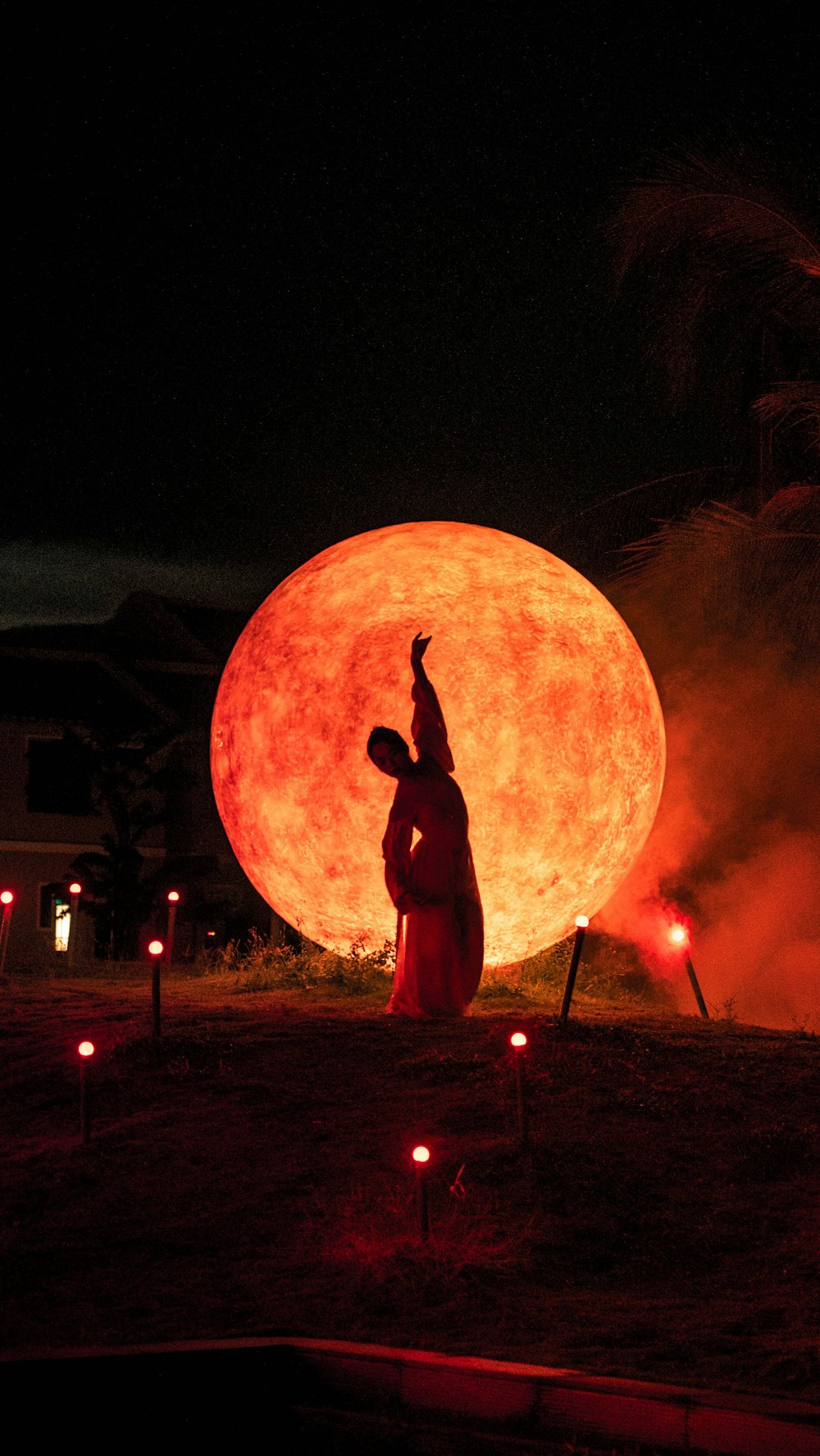 a person standing in front of a giant orange ball