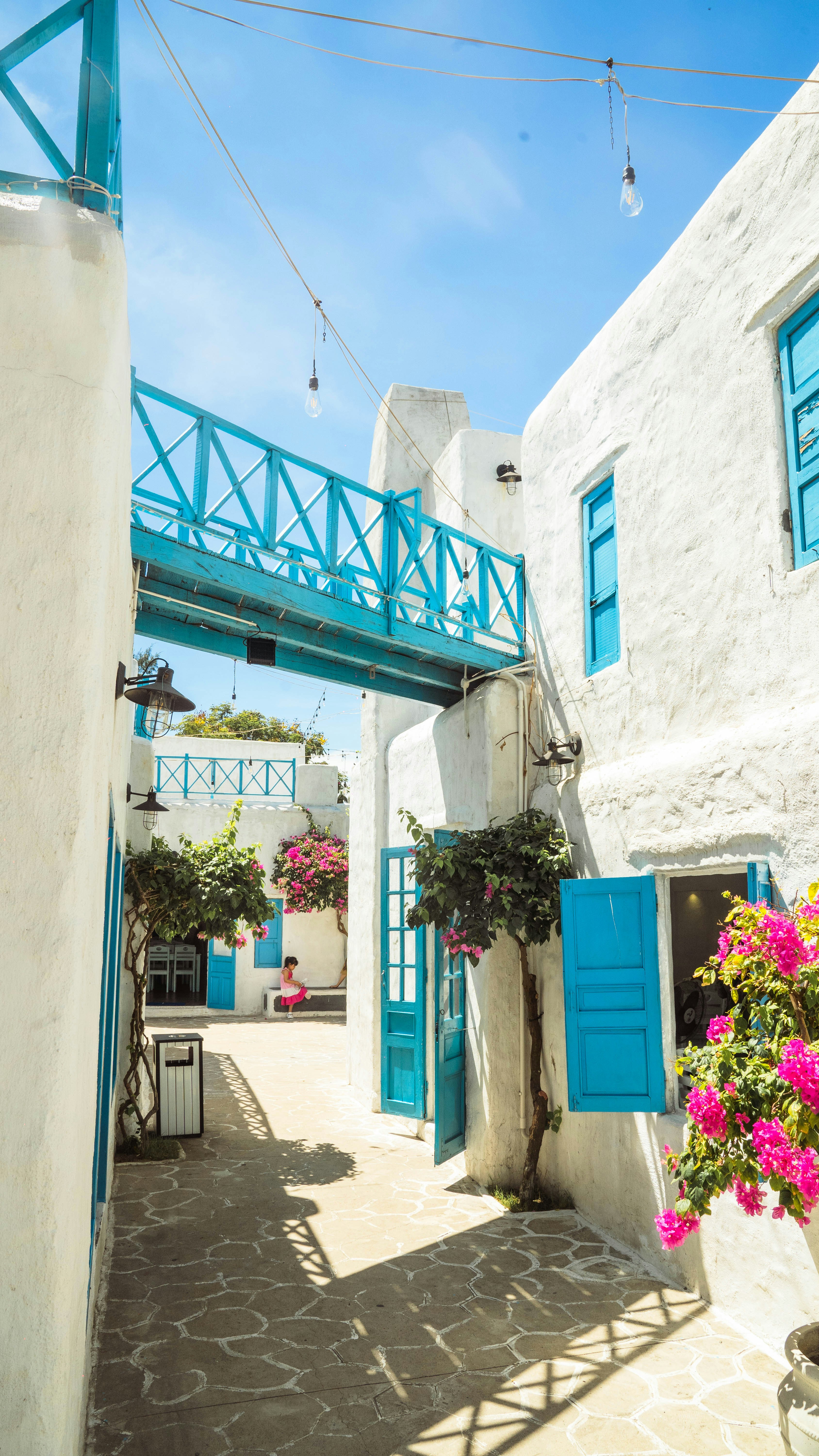 a white building with blue shutters and a blue bridge