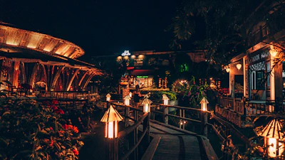 Evening view of a resort pathway lined with glowing lanterns and lush plants.