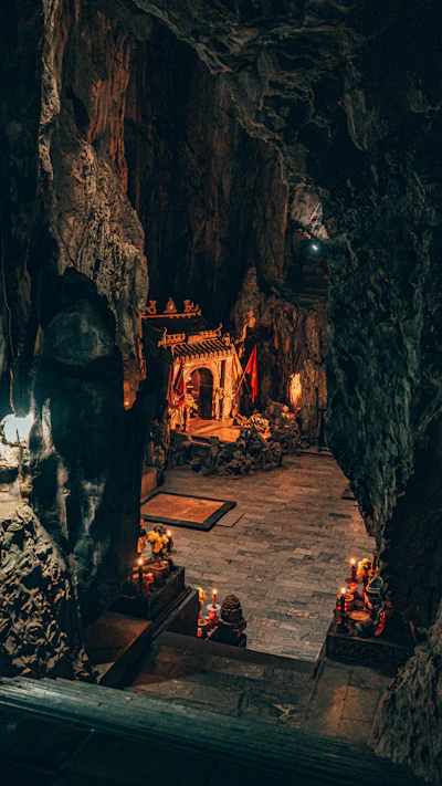 Candles and Buddhist statues inside a cave shrine at the Marble Mountains, Da Nang