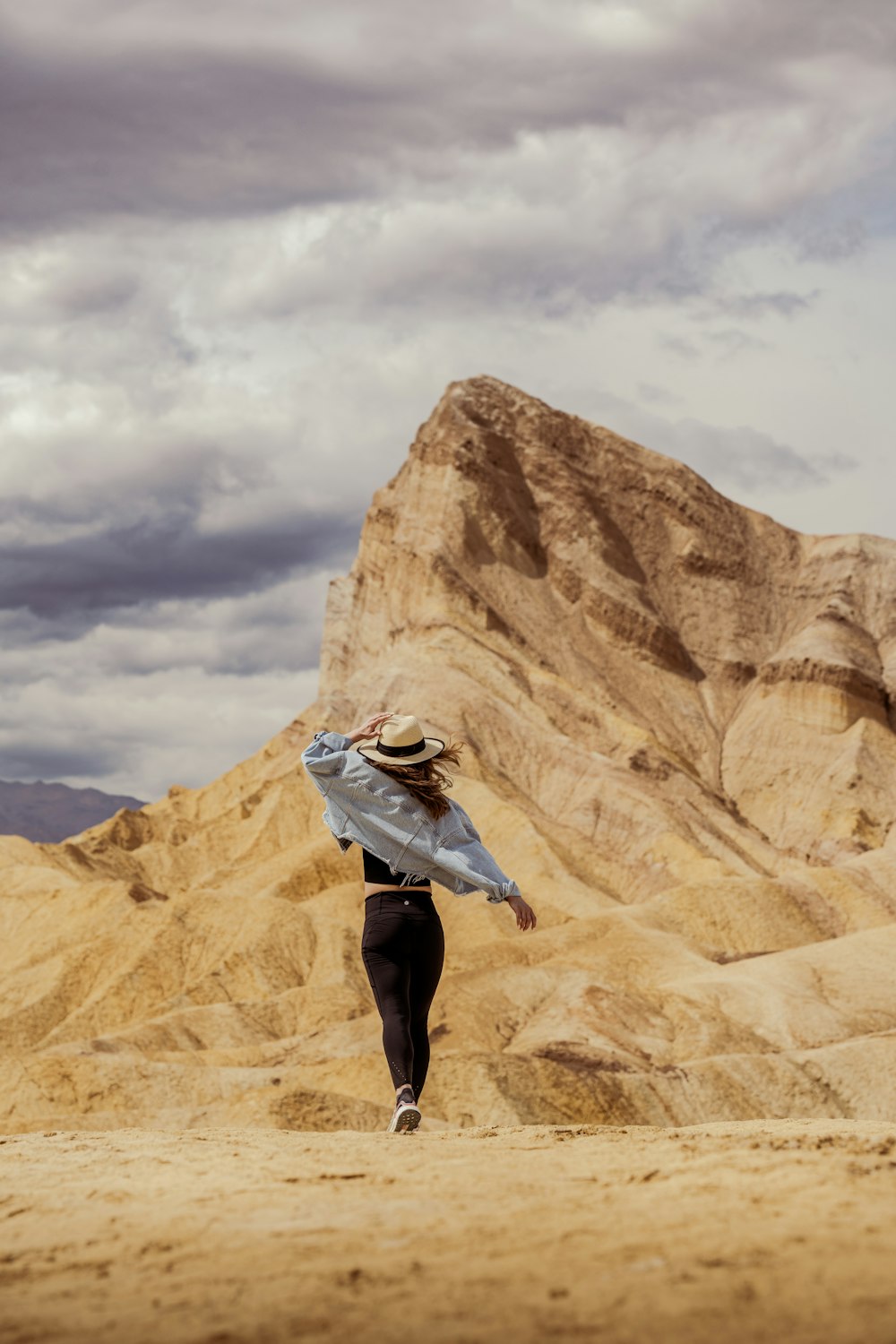 a woman in a hat is walking in the desert