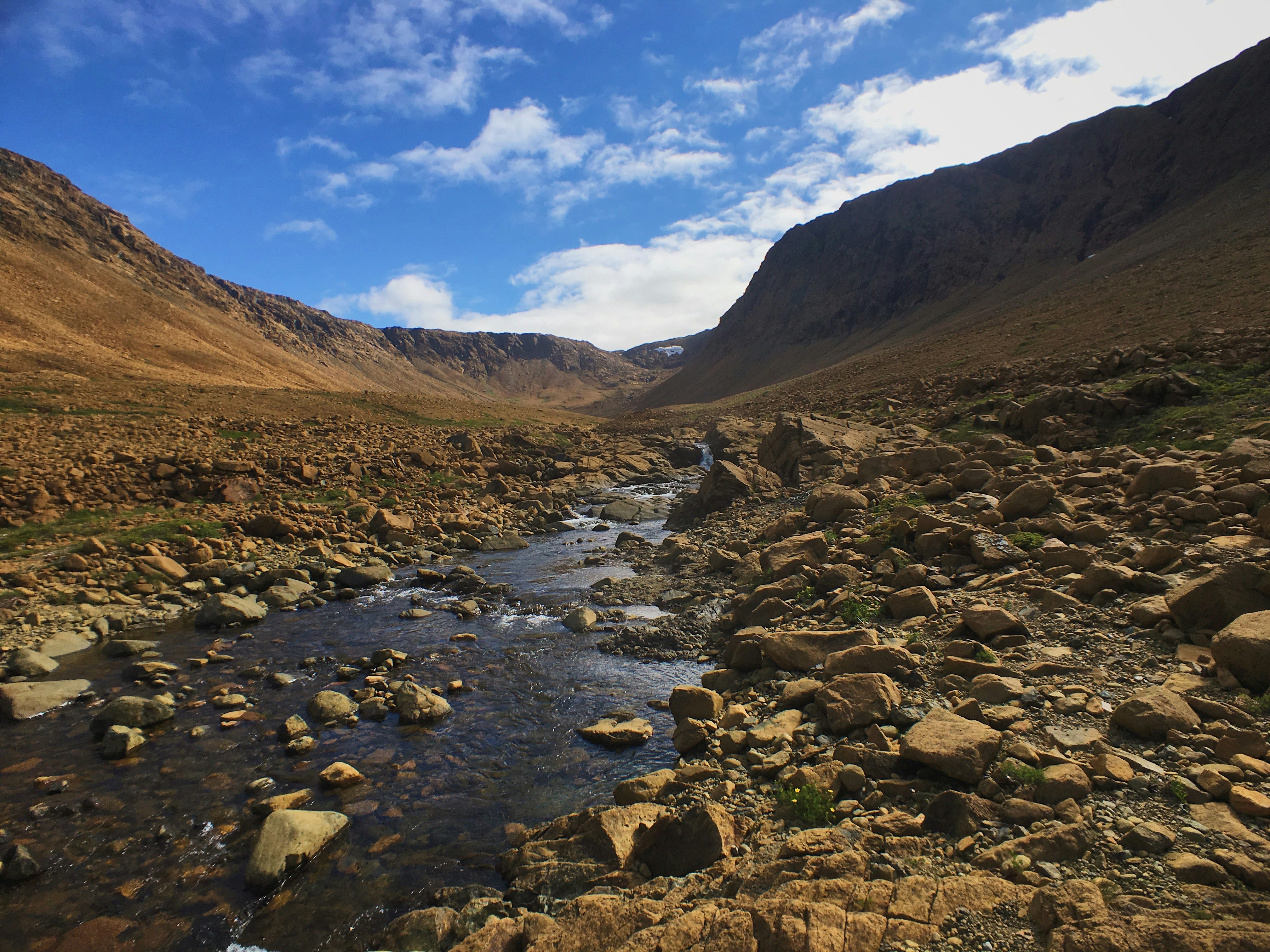 a rocky river running through a valley surrounded by mountains