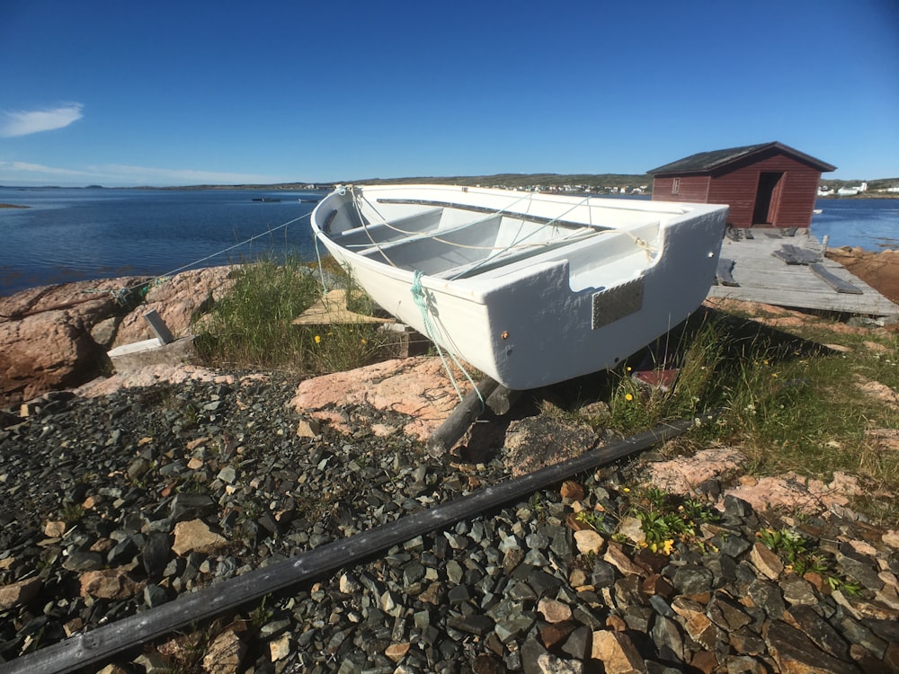 a white boat sitting on top of a rocky shore