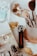 A variety of makeup brushes are neatly arranged in a holder, accompanied by several cosmetics items including a lipstick and perfume. The setting has an elegant yet casual feel, with soft lighting highlighting the textures and colors of the beauty products.