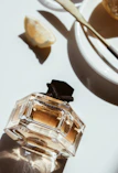 Someone layering different perfume sprays on wrist and neck, smiling softly in a sunlit room