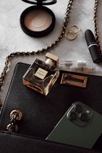 a black purse with a phone, lipstick, and other items on it