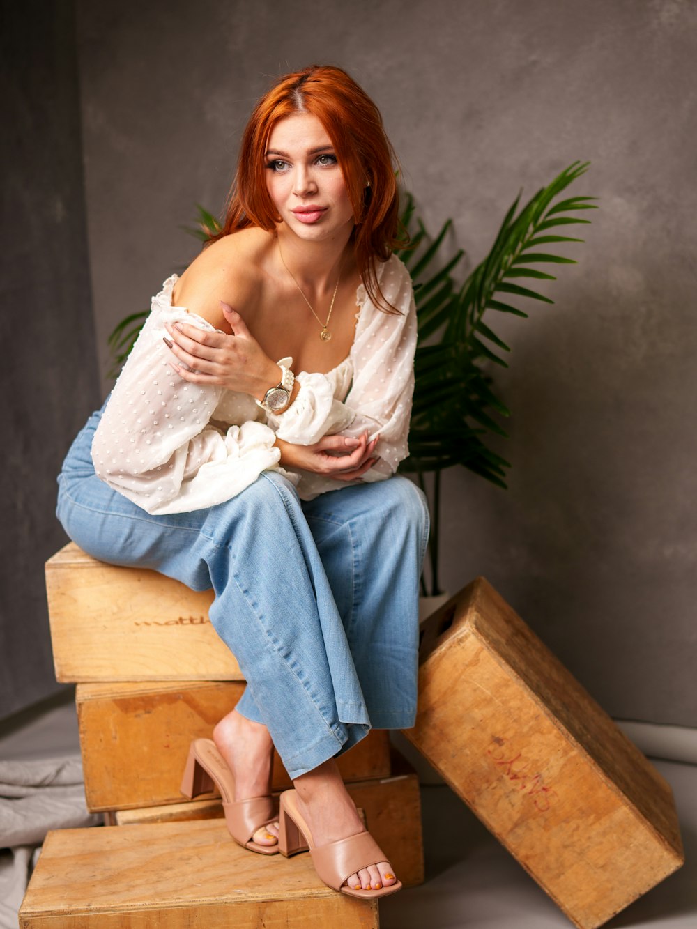 a woman with red hair sitting on a wooden box