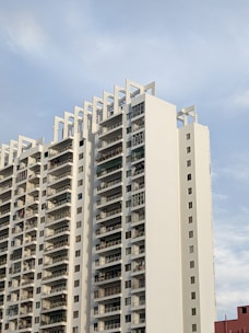 Modern urban apartment complex with rooftop terrace and city skyline in the background.