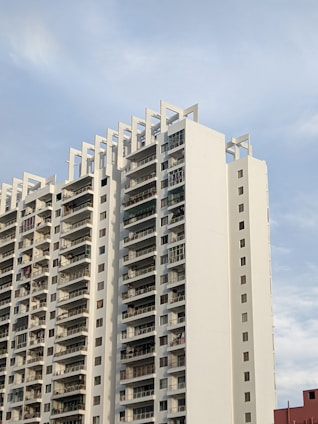 Modern urban apartment complex with rooftop terrace and city skyline in the background.