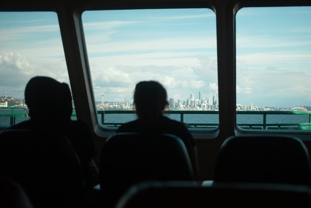 a couple of people sitting on a bus looking out the window