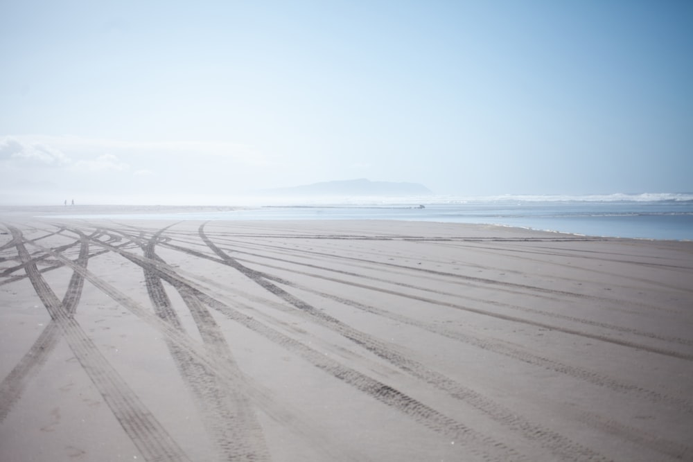 a sandy beach with tracks in the sand