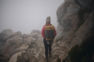 A hiker wearing a sleek traildry jacket, standing on a misty mountain trail with droplets beading on the fabric.