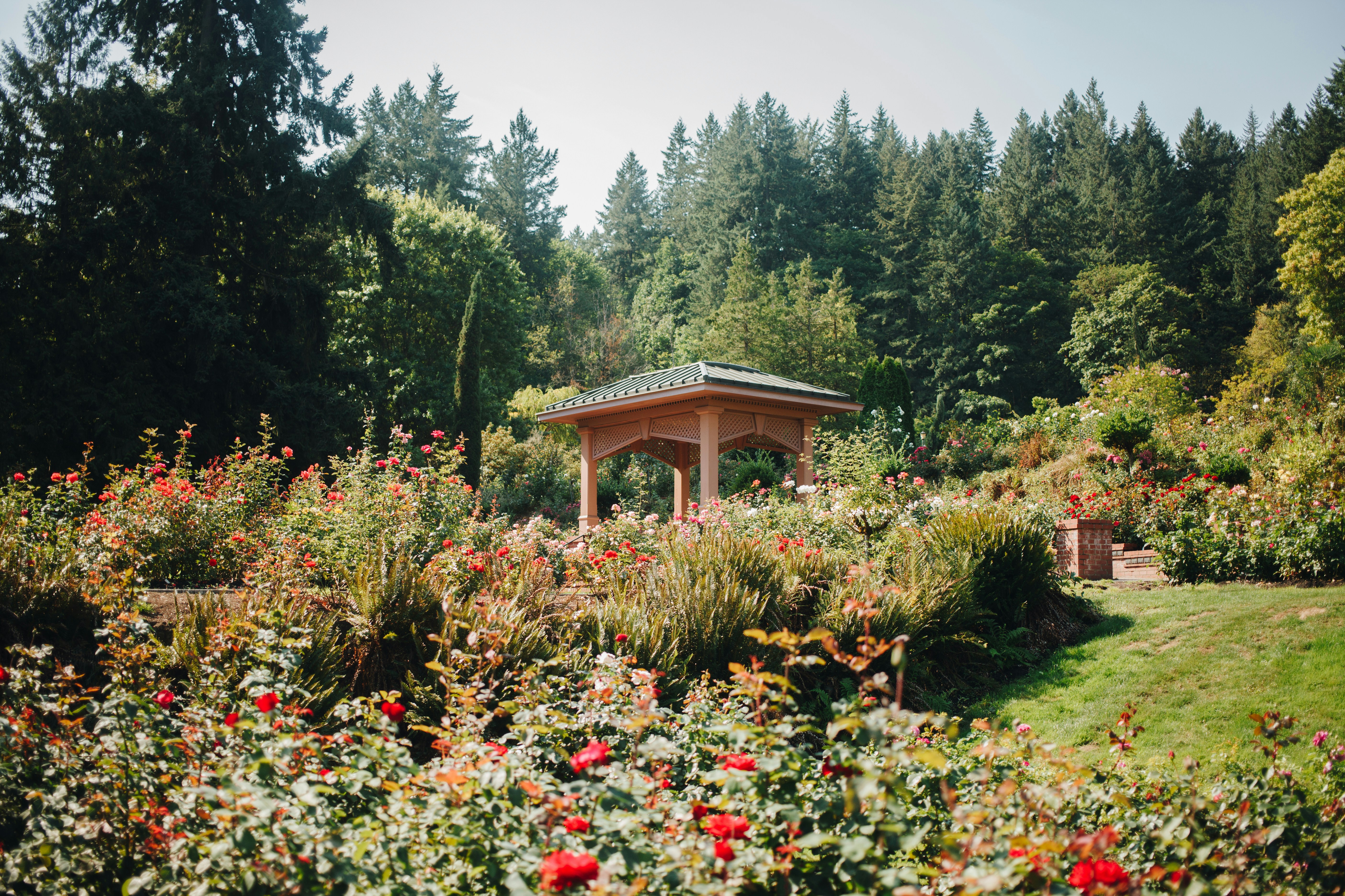 a gazebo surrounded by flowers and trees in a park